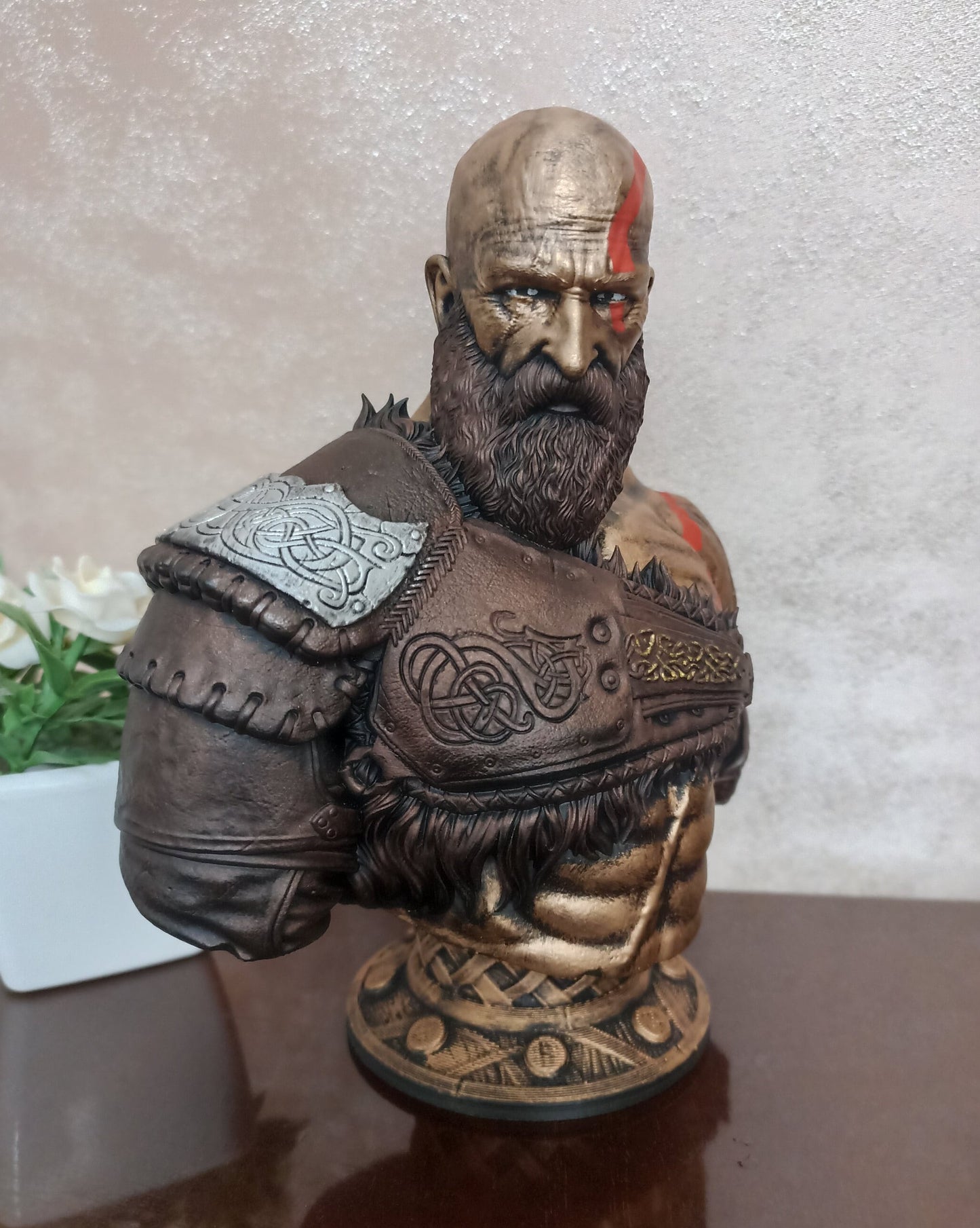 Bronze bust of a warrior with armor and tattoos on a neutral background